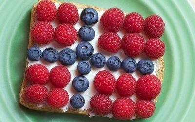 Skive med flaggpynt laget av kremost, bringebær og blåbær