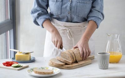 Kvinne skjærer brød til frokosten