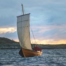 En geitbåt flyter på vannet i solnedgang