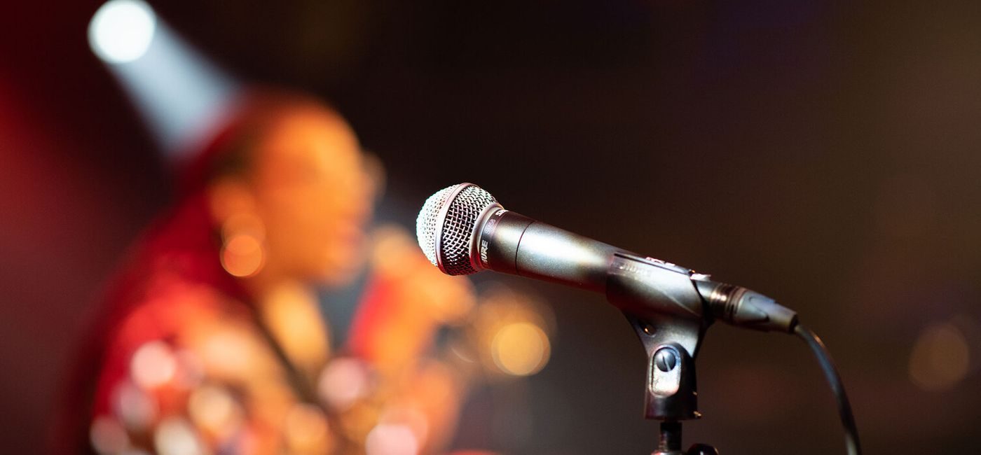 Mikrofon. Uskarp artist synger i bakgrunnen
