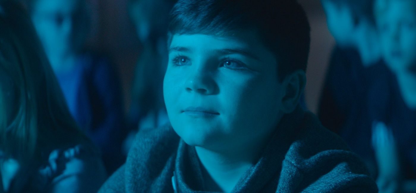 Gutt sitter i publikum, badet i blått scenelys.