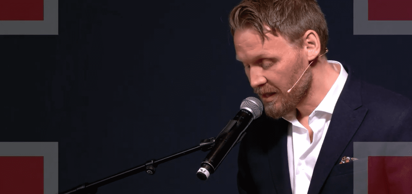 Mann står i profil mens han snakker i mikrofon