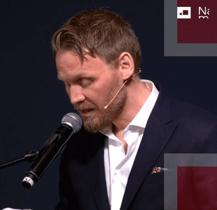 Mann står i profil mens han snakker i mikrofon