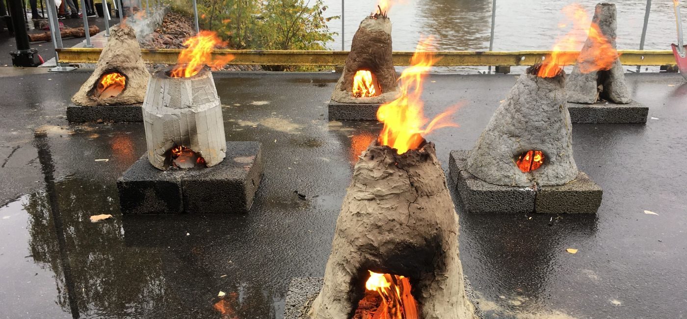 Små leirovner er i full fyr og står utstilt utendørs på hver sin stein.