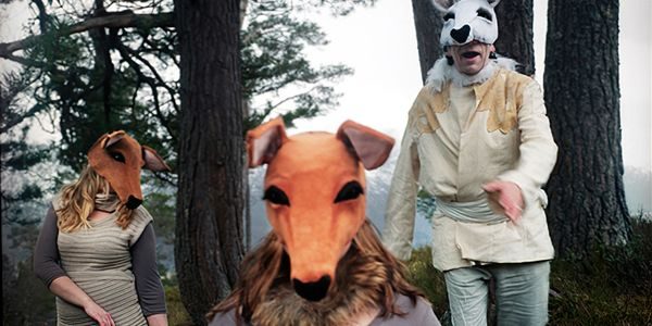 Tre personer i dyremasker poserer i en skog