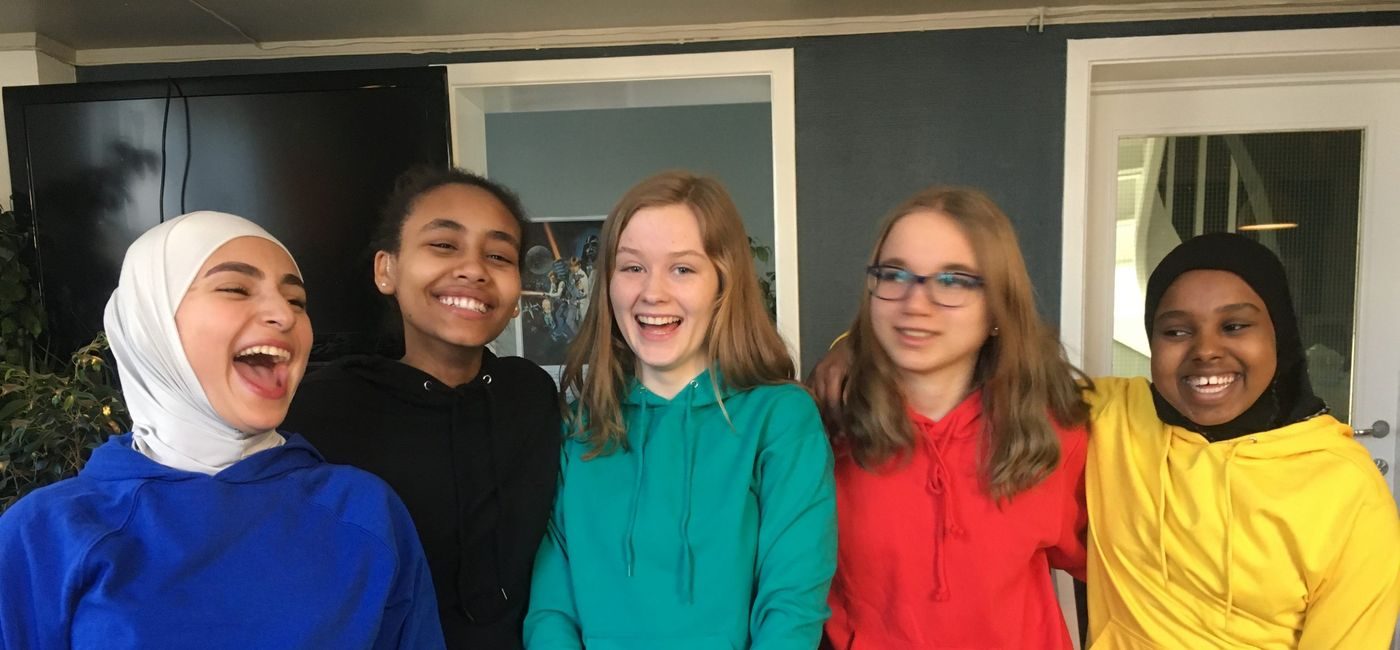 Fem jenter i fargerike hettegensere ler