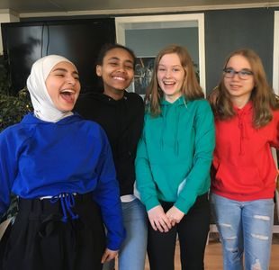 Fem jenter i fargerike hettegensere ler