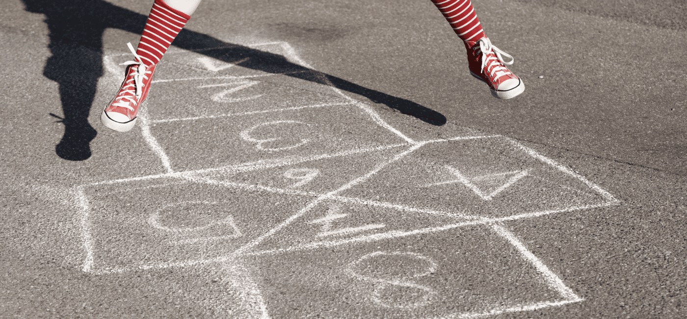 Jente hopper over et paradis tegnet med kritt