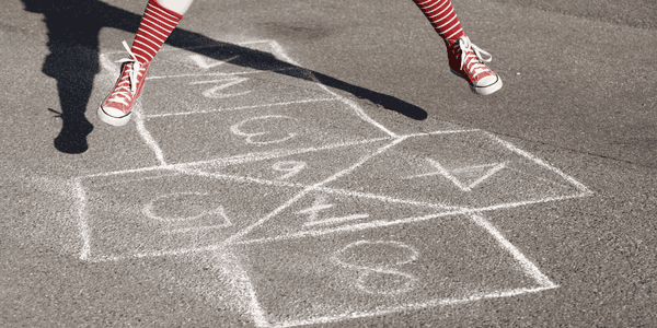 Jente hopper over et paradis tegnet med kritt