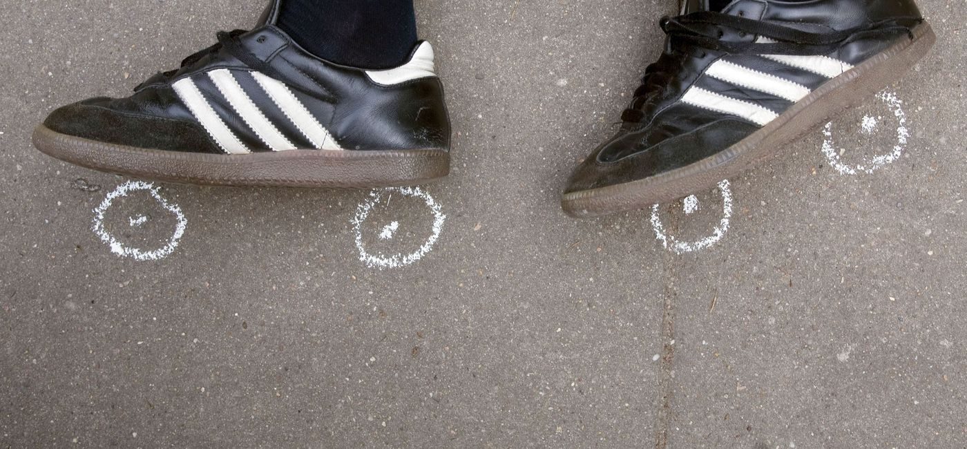 barn med sorte og hvite joggesko står ved hjul tegnet på med kritt