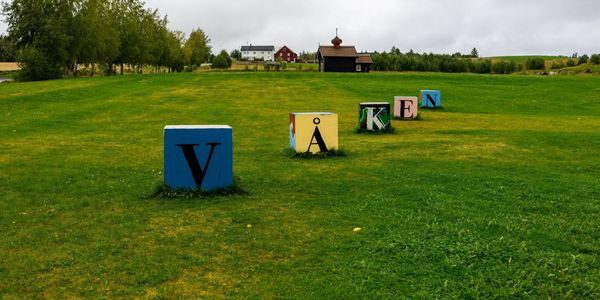 Kunstverk av klosser som gir ordet "våken" på en grønn eng.