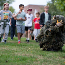 En gruppe elever går etter en person kledd i kamuflasje