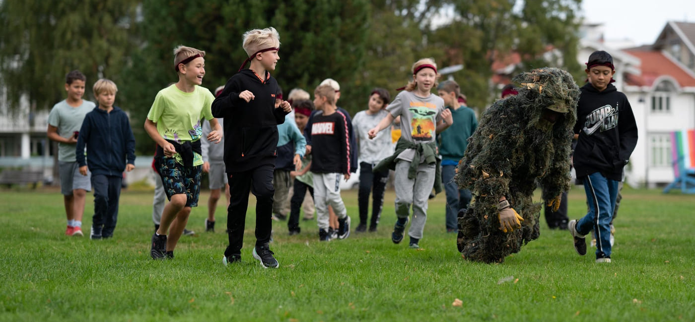 En gruppe elever går etter en person kledd i kamuflasje