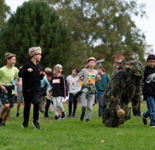 En gruppe elever går etter en person kledd i kamuflasje