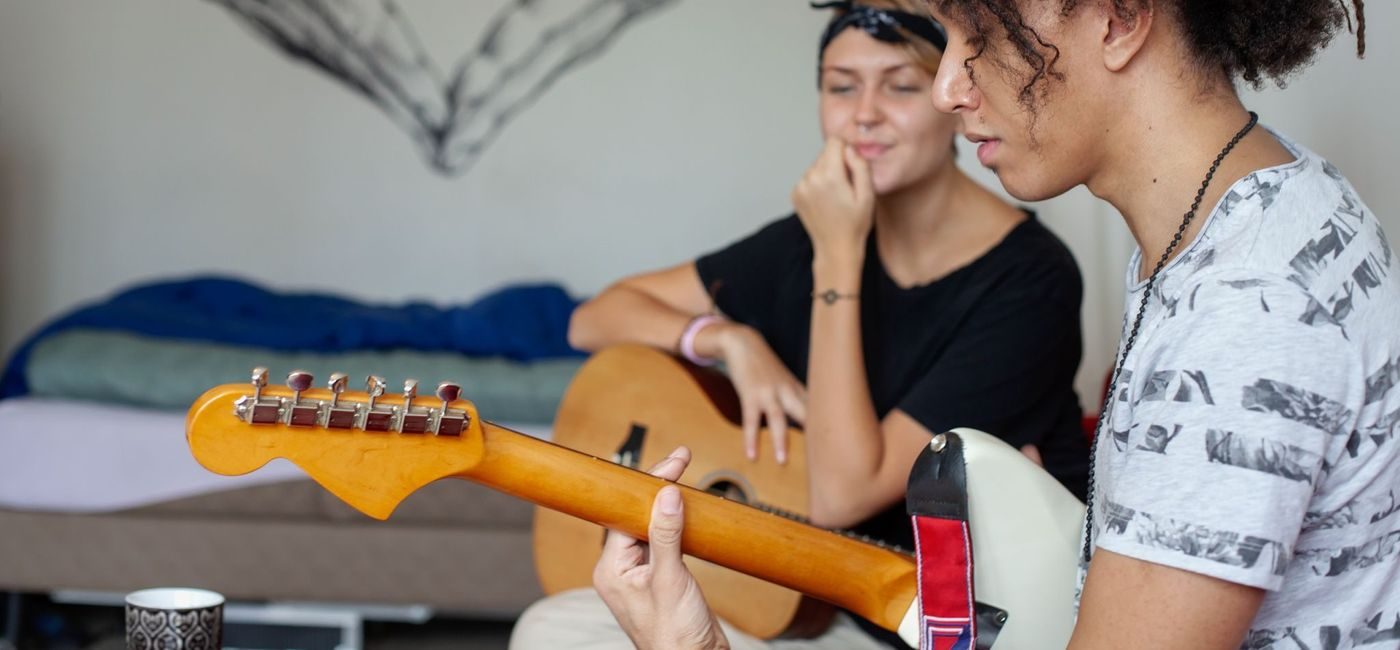 To ungdommer på et rom. Den ene spiller på en elektrisk gitar