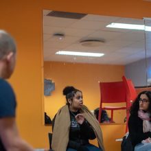 Tre elever snakker. En mann ser på dem