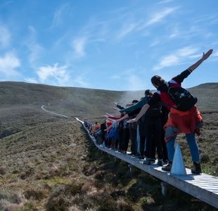 En gruppe personer balanserer på en smal trebro på øya Runde.