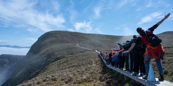 En gruppe personer balanserer på en smal trebro på øya Runde.