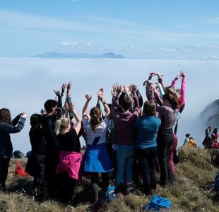 Elevgruppe står på toppen av et fjell med armene i været.