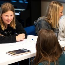 Forfatter Mari Moen Holsve sitter på hun foran en pult og prater med en elev