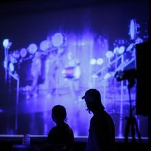 To personer ser på stort lerret som viser en video.