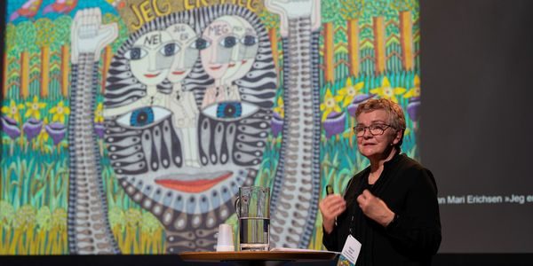 en dame kledd i sort står foran et fargerikt bilde