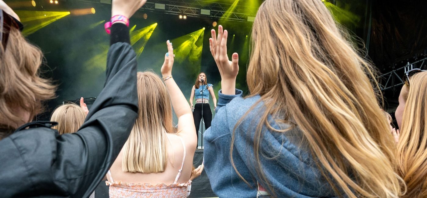 Artisten ISAK står på scenen. Vi ser ungdomemr bakfra som klapper entusiastisk.