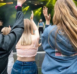 Artisten ISAK står på scenen. Vi ser ungdomemr bakfra som klapper entusiastisk.