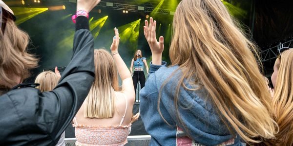 Artisten ISAK står på scenen. Vi ser ungdomemr bakfra som klapper entusiastisk.