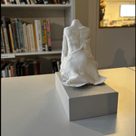 En hvit statue ses i forgrunnen. Bak er en bokhylle.