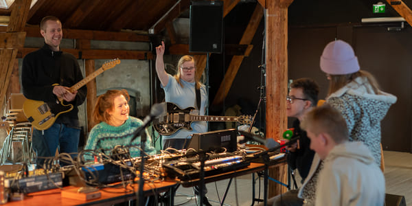 Fire ungdommer og to voksne spiller musikk sammen.