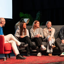 Fire ungdommer og en mann sitter i en stol og en sofa på en scene og snakker med hverandre.