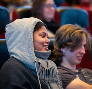 To ungdommer sitter i en kinorad og ler.