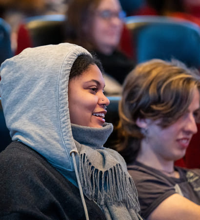 To ungdommer sitter i en kinorad og ler.