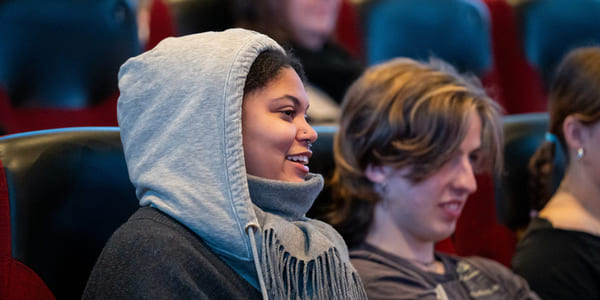 To ungdommer sitter i en kinorad og ler.