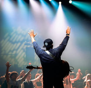 en mann står foran publikum. Han holder hendene i været.