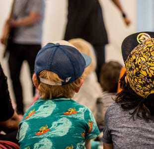 To barn med caps ser på en forestilling.