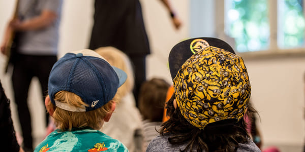 To barn med caps ser på en forestilling.