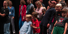 En stor gruppe mennesker. Mange går to og to, hvor den ene lener seg bakover mot den andre.