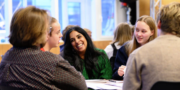 Kultur- og likestillingsministeren sitter ved et bord med ungdommer.