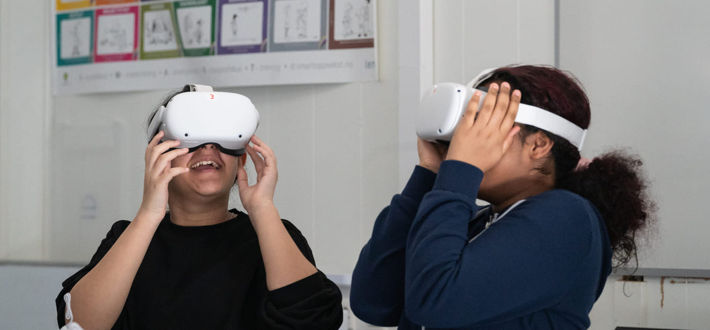 To barn har på seg hvert sitt VR-sett og smiler.