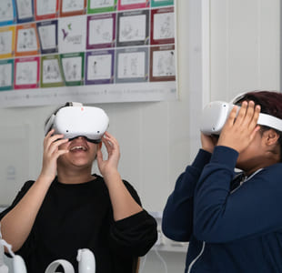 To barn har på seg hvert sitt VR-sett og smiler.