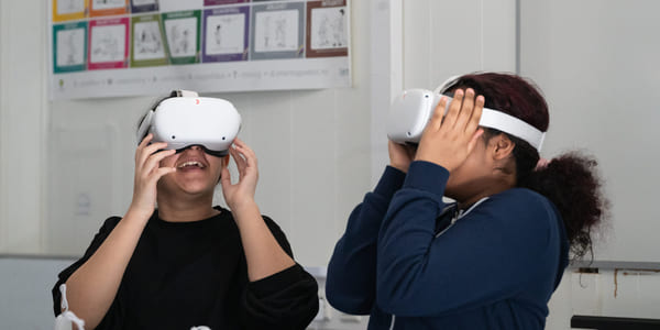 To barn har på seg hvert sitt VR-sett og smiler.