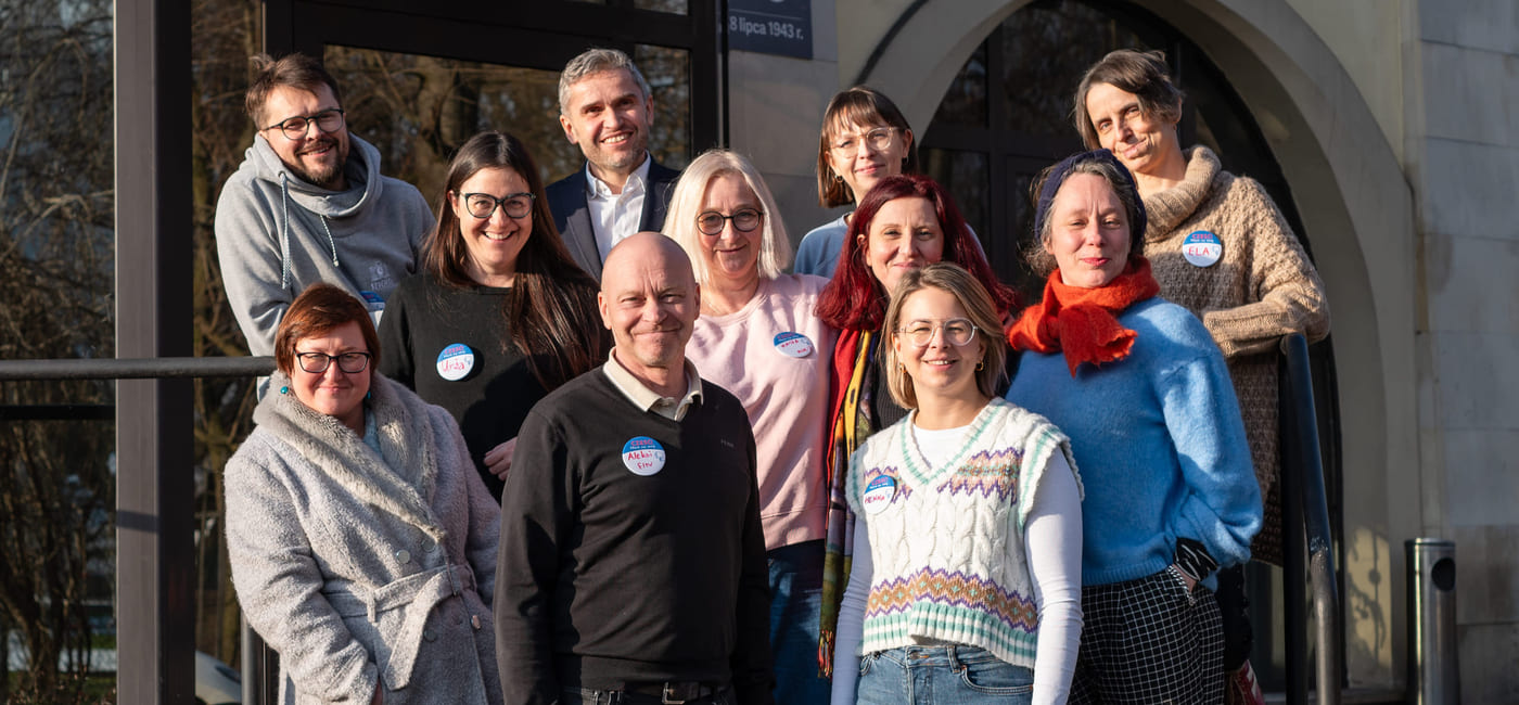 En gruppe med kvinner og men står på en trapp foran en bygning