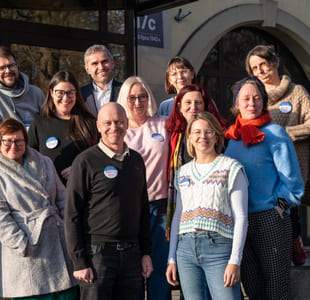 En gruppe med kvinner og men står på en trapp foran en bygning