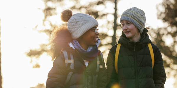 To jenter er ute og går. De smiler og ser på hverandre.