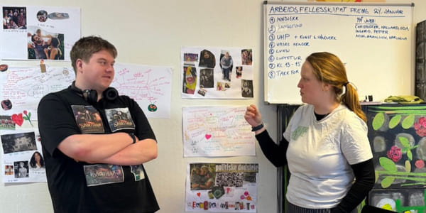 To personer står foran en plansjeutstilling og snakker sammen