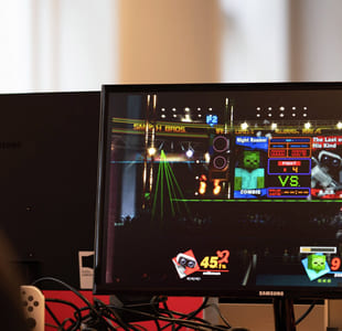 En person spiller et digitalt spill på storskjerm med fargerike elementer og animasjoner.