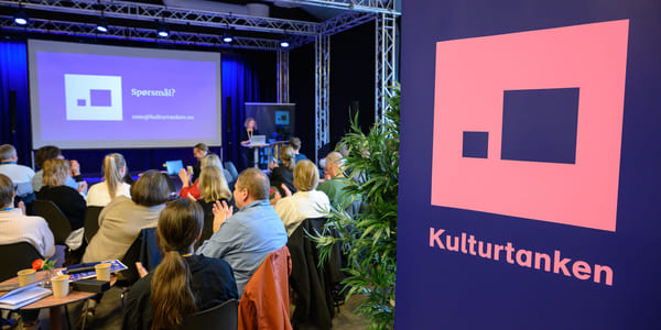 Sittende publikum ser på en presentasjon. Kulturtanken-logo på rollup i forgrunnen.