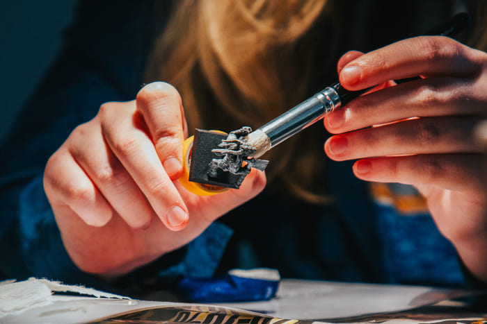 To hender arbeider med loddebolt og små elektroniske komponenter i et teknologiprosjekt.